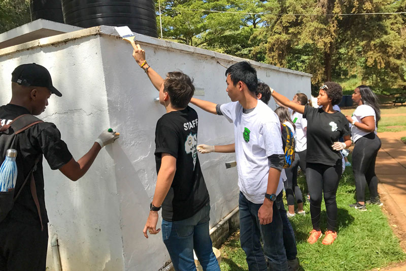 Durante la Cumbre de Servicios de Problemas Globales de AISA (GISS) de 2018 organizada por la Escuela Internacional de Kenia, los estudiantes pintan un baño público en la Reserva Forestal de Karura como parte de las actividades de servicio para la cumbre.