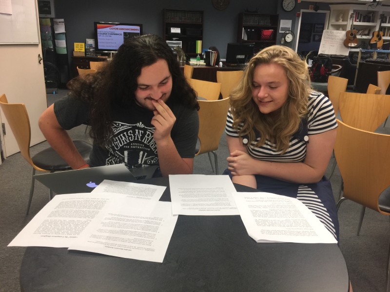 Two students help each other edit essays for their Senior Seminar English Class.