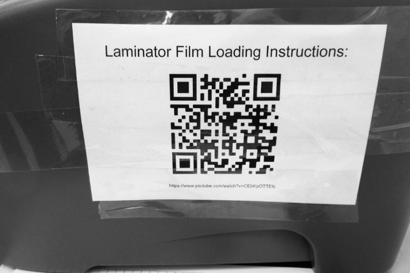 QR codes are used for staff to access laminator film loading instructions