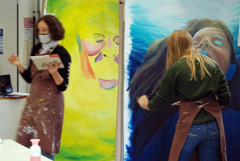 Dos estudiantes comenzando sus grandes pinturas. Los estudiantes comenzaron con una pintura base y luego comenzaron a bloquear su retrato.