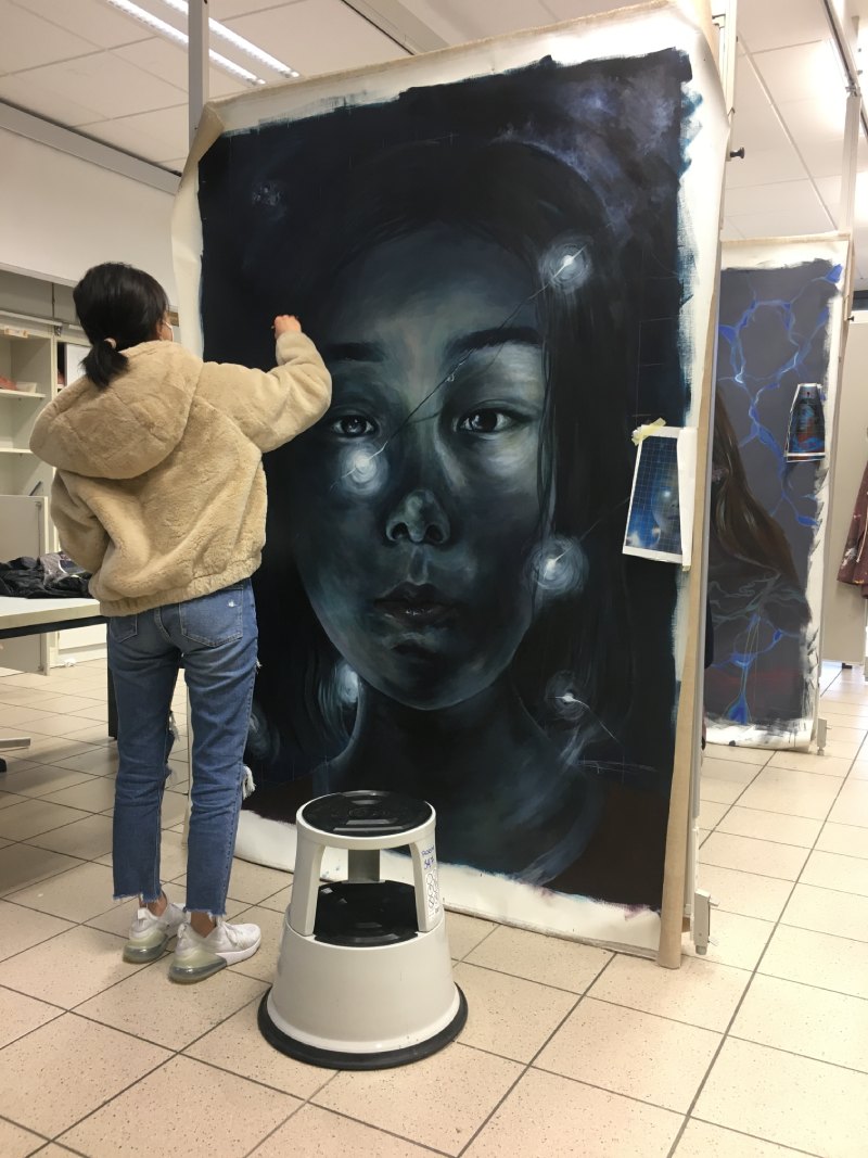 Student adding the final details to her artwork that towers above her head.