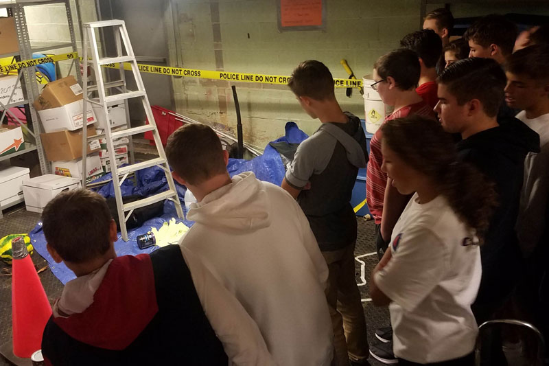 Los estudiantes en su clase de ciencias de noveno grado están inspeccionando una escena de crimen simulada para aprender las habilidades de observación. Este es el tipo de actividad que no se puede replicar a través del entorno de aprendizaje a distancia.